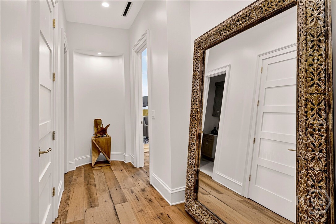 Foyer - Central corridor offers a clean, symmetrical transition between living areas and private quarters. Framed by multiple doorways and natural wood flooring, the layout emphasizes linear flow and architectural clarity. A recessed niche at the end provides a focal point for art or sculpture.