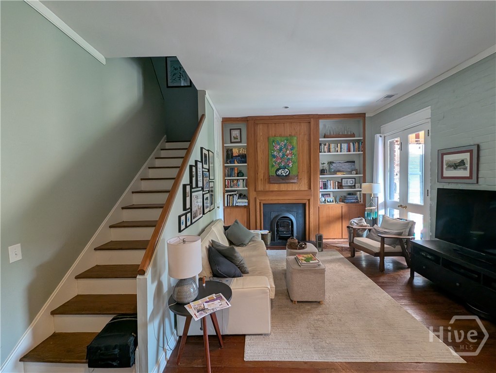 Living Room with fireplace and heart pine floors, double French doors facing rear Courtyard.  Large storage closet with shelving under stairs.