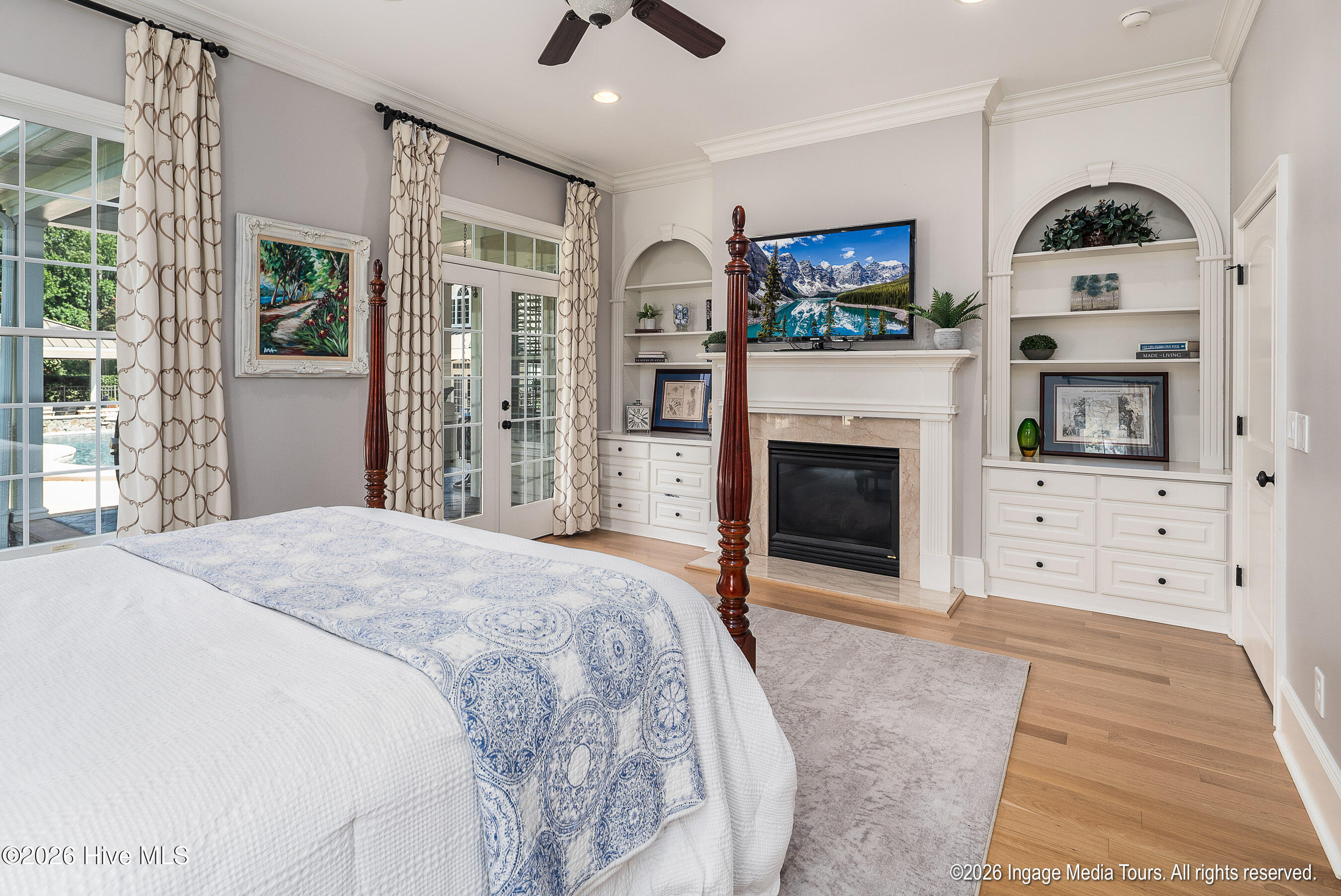 Downstairs Primary Suite with Fireplace and french door for to back terrace overlooking pool.