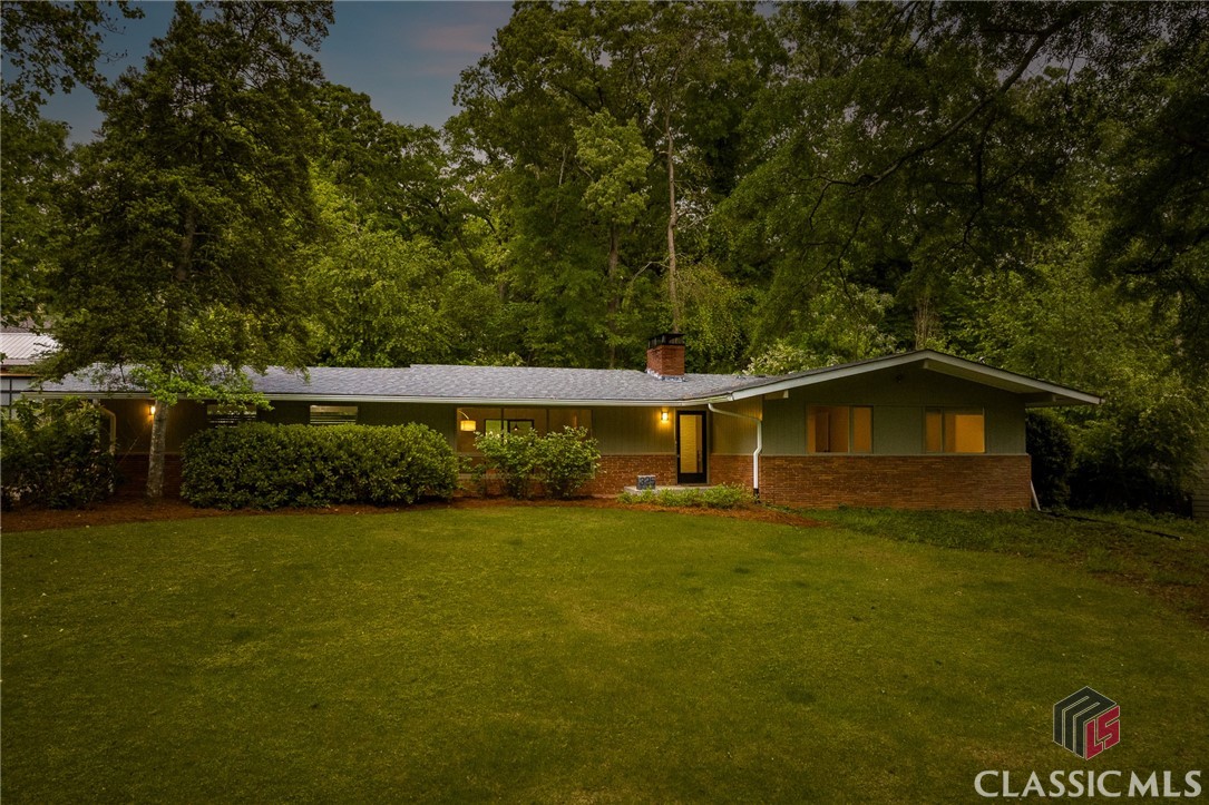 Mid Century Modern lover’s delight located in the Five Points neighborhood of Bedgood-Glenwood! Sited atop a lovely, half-acre lot with a lush Zoysia lawn and located across the street from the Middle Oconee River, this location cannot be beat. The entry foyer is warm and bright, featuring original flagstone flooring and exposed brick wall. To the left is the living room with vaulted ceiling, huge picture window, exposed beams, an oversized fireplace with firewood storage, and clerestory windows at the roof gable that add an extra zing of mid-mod flare. Finished concrete floors run throughout the living and dining areas while original oak flooring runs through the kitchen, den/ lounge, and all three bedrooms. Sliding glass doors in dining and den open to a sunken patio surrounded by flowering perennials. Both the back and front yards are substantial in size allowing flexibility for someone with a green thumb or someone looking to expand the home’s footprint. Stainless steel appliances - including a Fisher-Paykel refrigerator, granite countertops, unique storage shelves, and hardwood floors complete the spacious kitchen. Don't miss the funky hallway railing at the basement stairwell! Owner's Suite located on the main level has many possibilities with en-suite bath and dual closets. Two additional bedrooms are just around the corner and share a spacious hall bathroom. The basement offers ample storage or room to expand. Whether its use is a home gym, teen suite, or studio, there are many ways one can utilize the space. Large, fenced backyard is sunny and perfect for gardening, gatherings, or Fido play space. Consider your fancy tickled - call your Realtor today before this opportunity vanishes!