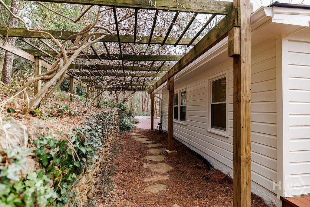 Walkway with arbor and stone wall behind the house