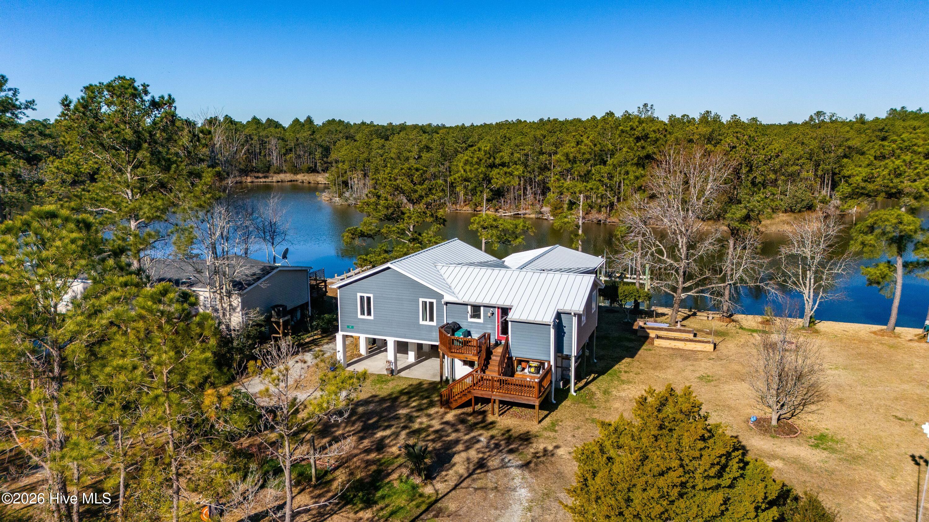 Waterfront home on scenic Buxton Creek, offering easy access to the Pamlico Sound and Intracoastal Waterway and a relaxed coastal lifestyle. This well-maintained 2-bedroom, 2-bath residence combines quality construction, thoughtful updates, and inviting outdoor living in a peaceful creekfront setting.Carefully maintained and improved, the home features a metal roof, updated HVAC system, newer kitchen appliances, and generator-ready wiring. Elevated in 2004, the home provides excellent protection along with a finished enclosed area beneath, ideal for storage, hobbies, or workshop space, complete with built-in workbenches, extensive shelving, a propane wall heater, and covered parking for two vehicles. Two shop doors were replaced in 2025.Inside, the updated kitchen offers soft-close cabinetry and a dual-fuel range, while the living area is comfortable year-round with a mini-split system, propane parlor stove, and sliding glass door leading to outdoor spaces. The hot water heater was replaced in 2024, adding to the home's list of recent improvements.Outdoor living is a highlight, with a covered porch and deck overlooking Buxton Creek—perfect for morning coffee or evening relaxation. Boaters will appreciate the boathouse with a 16,000-lb lift and new roof (2025) and approximately five feet of water depth at the dock, making time on the water convenient and enjoyable. Additional features include LeafFilter gutter protection and low-maintenance exterior finishes.Whether used as a full-time residence or a waterfront retreat, this property offers a comfortable, well-cared-for home in a quiet creekfront setting with excellent boating access.