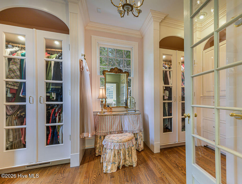 Primary suite private dressing room with built-in glass arched wardrobe closets with built-in and retracting shoe storage.