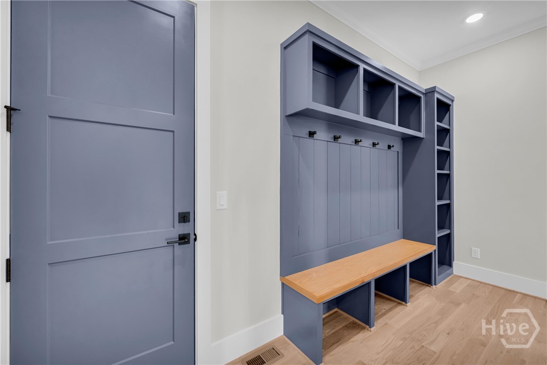 Mudroom featuring custom blue built-in cabinetry with bench seating, open shelving, and coat hooks