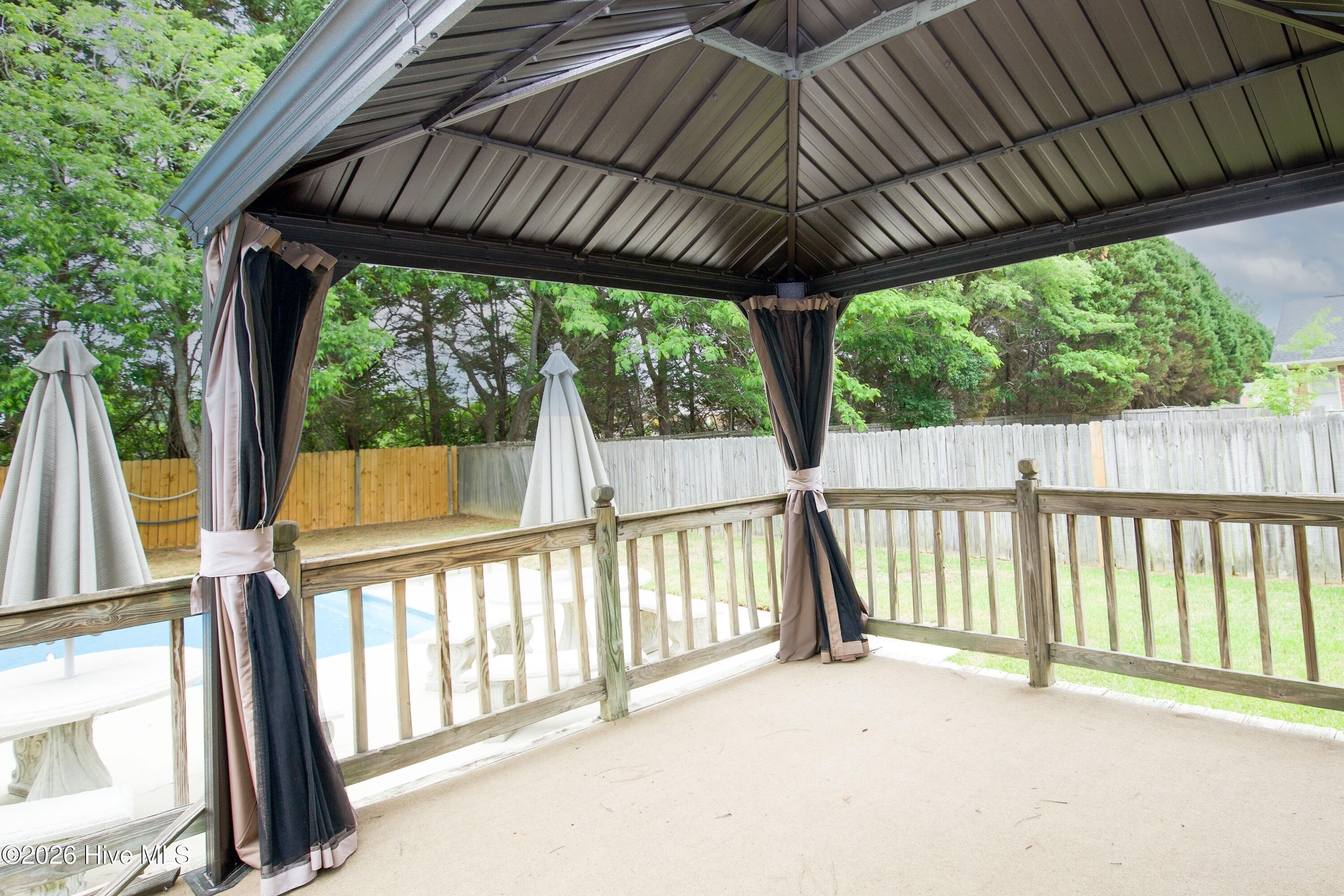 Spacious covered gazebo with elevated views of the fenced backyard and pool area creates a peaceful outdoor retreat with room for seating, dining, and relaxation. Mature trees and established landscaping enhance the private atmosphere while providing a functional extension of the home’s living space. Perfect for enjoying North Carolina evenings, hosting gatherings, or creating a comfortable outdoor lounge area near Fort Bragg and Fayetteville amenities.