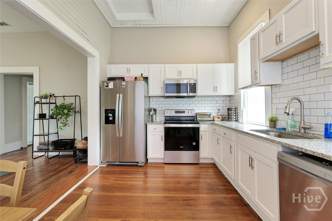 Updated kitchen with white cabinetry, granite countertops, stainless steel appliances, and abundant natural light.