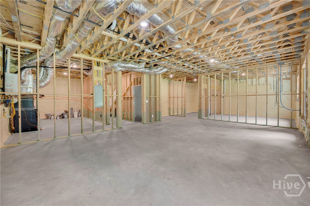 Unfinished basement space featuring exposed wood framing, concrete flooring, and recessed ceiling lighting