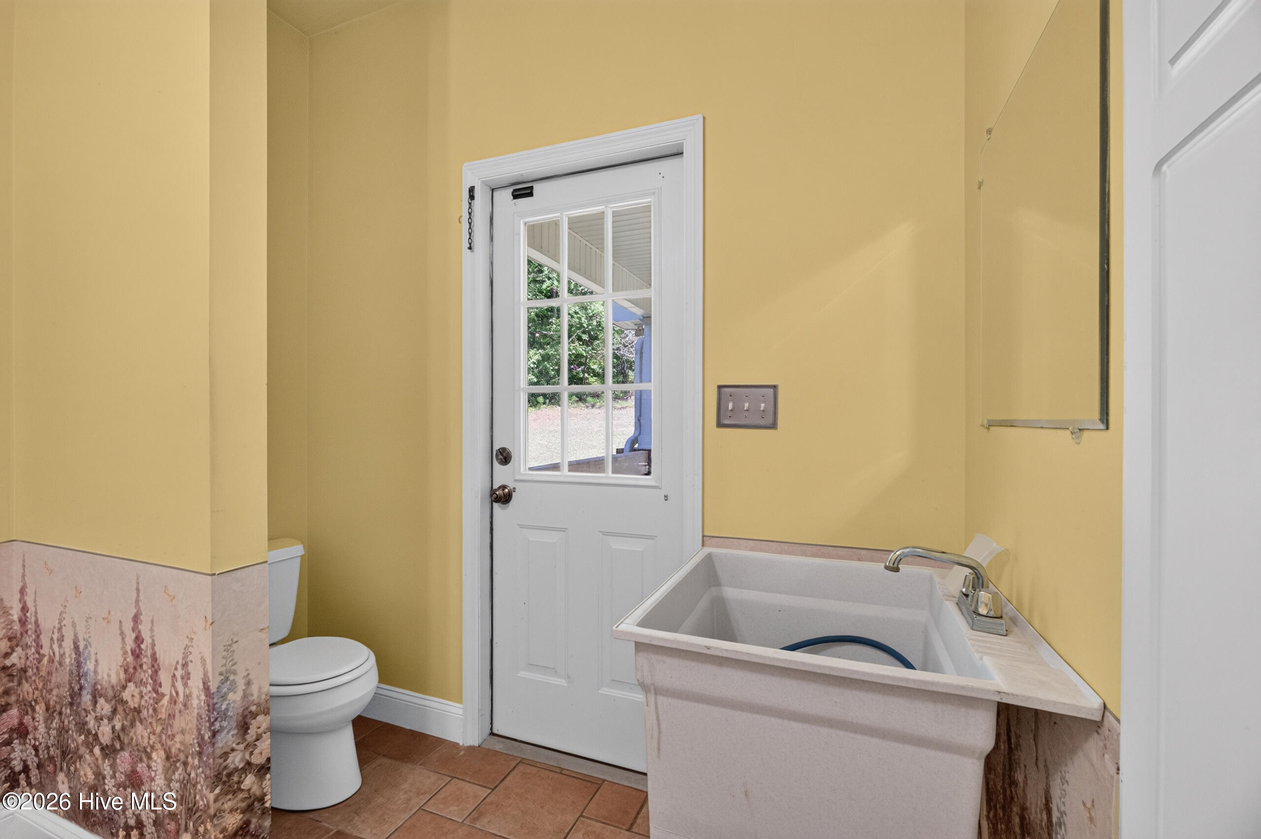 Spacious laundry room w/ tucked-away toilet; exit door leads to wrap-around front porch