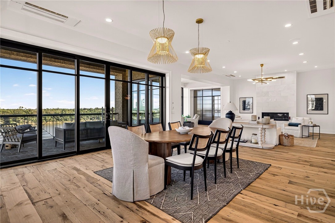 Open-concept living and dining with balcony access. This open-concept layout blends dining, living, and outdoor access into a unified, light-filled experience. Floor-to-ceiling glass doors extend the living space to a private balcony, while the fireplace and ceiling design anchor the interior zones. A sophisticated setting for indoor-outdoor living and entertaining.