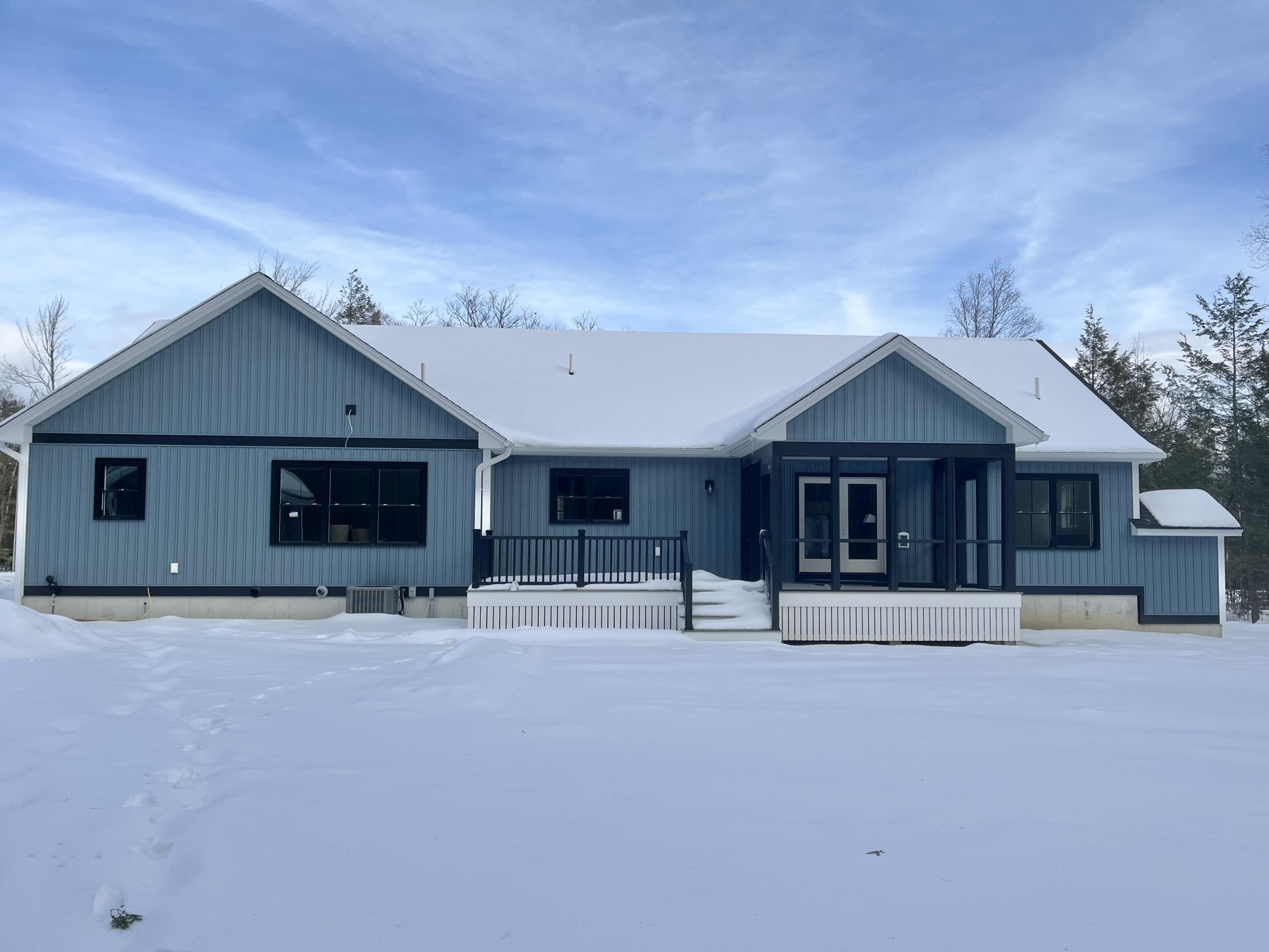 Blue single-story home with a covered glass entry and snow-covered roof, surrounded by deep snow.