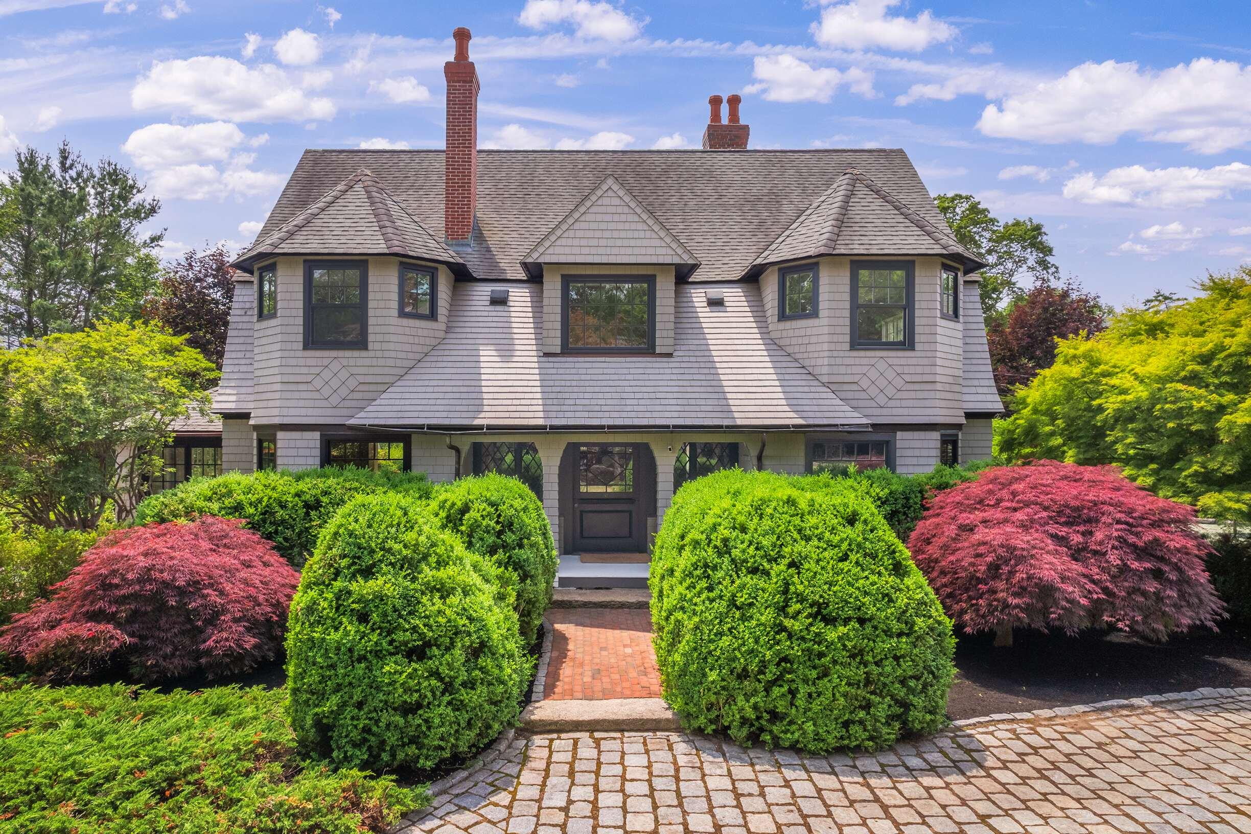 The Haven, built around 1890, is an exquisite estate located in the heart of York Harbor. The property features a charming cobblestone driveway and beautifully landscaped Victorian-style gardens, creating an inviting atmosphere. It boasts a newly laid brick patio with quiet spots for reflection, as well as a covered entrance with a wide Dutch front door. Inside, the impressive entryway leads to a formal dining room on the right, complete with a fireplace and built-in window seating. To the left, you'll find a spacious living room and game room. A glass-enclosed porch, accessible through double glass doors, opens up to a stunning side yard. The new, modern kitchen features peninsula seating, new appliances, and glass knobs on the cabinets, all while overlooking a large family area that opens to the patio and grilling space, making indoor and outdoor entertaining effortless. On the opposite side of the family room, there is a laundry room and a half bath. Upstairs, you will find multiple bedroom options, some equipped with dressing areas. The bathrooms are fitted with tiled showers, and one of the four bathrooms includes a classic clawfoot tub. A handsome library, complete with a decorative mantel and fireplace, adds to the home's allure. The third floor includes an office and ample storage closets. The basement has been transformed into a rustic speakeasy featuring a bar and fireplace, along with a gym that includes a sauna and shower area. The Haven is surrounded by formal garden paths, mature trees, and hedges, providing privacy. The property is just a short walk from Harbor Beach and offers easy access to a peaceful stroll along the York River via the Fisherman's Walk.