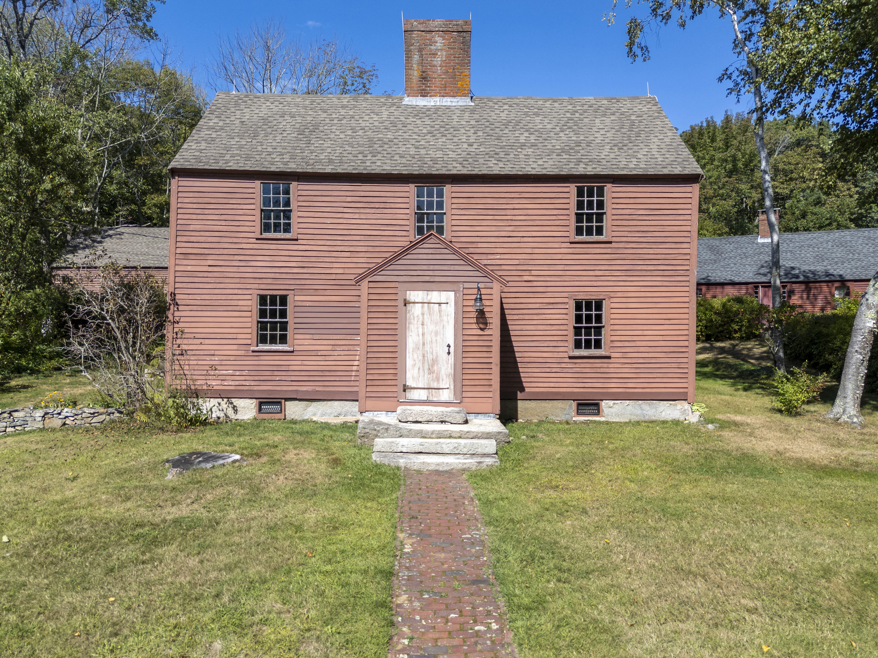 Own a piece of Maine history! This circa 1740 Georgian-style home is one of three antique homes comprising the John Sedgley Homestead. Set on 6.4 acres, the property is recognized as the oldest homestead still in its original setting in Maine and is listed on the National Register of Historic Places. Beautifully maintained, the home blends authentic 18th-century character with modern living. Extensive renovations were completed in 2014. The Keeping Room features a large working fireplace, offering an opportunity to cook and gather in the tradition of centuries past. The adjoining parlor provides a second professionally maintained working fireplace, ideal for formal entertaining. The classically styled kitchen includes custom cabinetry, modern appliances, soapstone countertops, and a comfortable dining area. A cozy den with French doors opens to a brick patio enclosed by beautiful stone walls. Upstairs, the primary suite offers a walk-in closet and private bath. Two additional bedrooms and a second full bath with a deep soaking tub provide space for family and guests. Built-in hallway storage and an enclosed washer/dryer add convenience. Hardwood floors throughout add warmth and continuity throughout the home. A 960-square-foot barn with loft offers flexible space for a workshop, storage, or creative pursuits. A peaceful wooded path leads to a secluded clearing with heirloom fruit trees. More than an antique home, this is an opportunity to become the next steward of Maine history. Come experience the character, craftsmanship, and tranquility of this remarkable homestead. The Homestead consists of three separately owned homes sharing the 6.4-acre parcel. Owners share the driveway, well, and septic system as established in the condominium declaration; owners maintain their individual homes. Showings Start at Open House: 9/12 & 9/13, 1-3 PM.